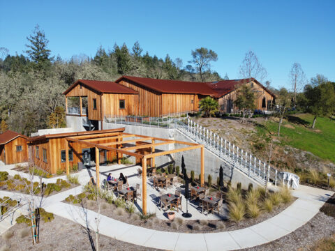 Modern wooden hillside building with outdoor patio seating