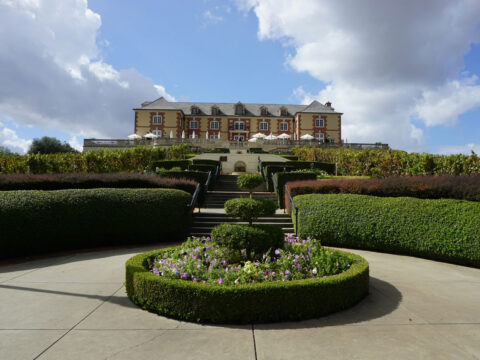 Grand mansion above manicured formal garden and hedges