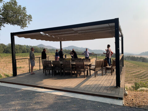 People standing on deck overlooking vineyard hills