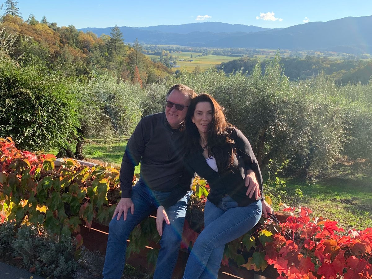 Couple sitting amid autumn vineyard with mountain view