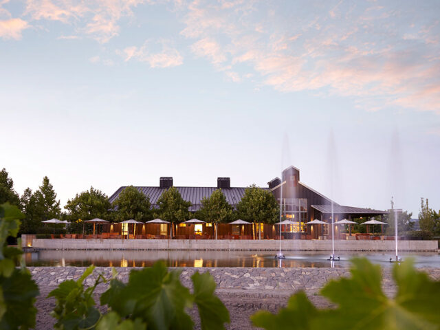 Modern lakeside building with fountains at sunset